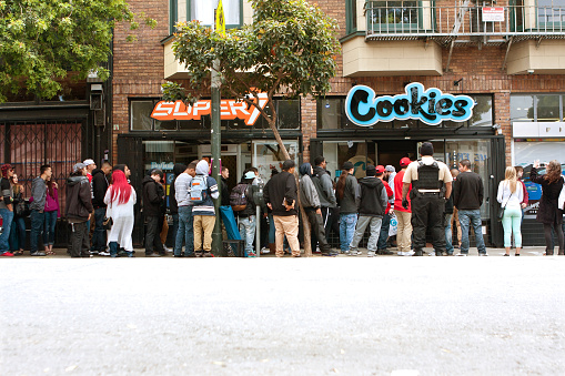 San Francisco, CA, USA - May 15, 2015:  A very long line of people waits to get into a new Cookies store in the Haight Ashbury section of San Francisco.  Cookies sells clothes and maijuana-related swag and accessories.