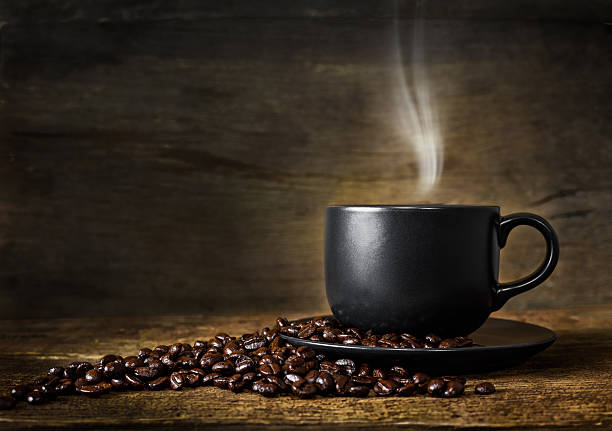 Cup of hot coffee and coffee beans on old wood background