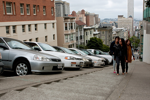 San Francisco, CA, USA - May 18, 2015:  Young Asian women climb a very steep set of concrete steps in the Nob Hill area of San Francisco.