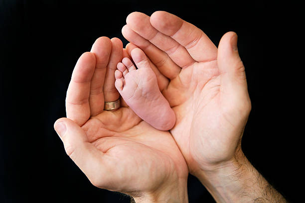 istock Father's Hands Cupping Newborn's Foot 488543578