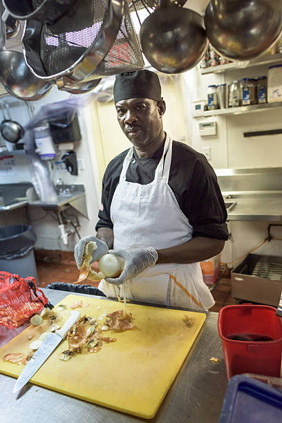 Cook at the kitchen black man posing at his restaurant kitchen preparing food, peeling onions retro 1950s kitchen stock pictures, royalty-free photos & images