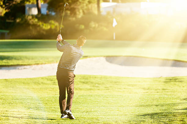 istock Young golfer trying to avoid sandtrap with lofted shot 488553480