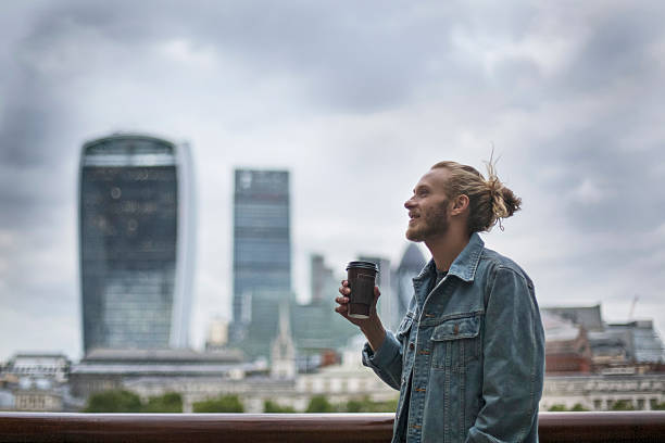 uomo pensieroso hipster bere caffè nella street a londra - denim jacket foto e immagini stock