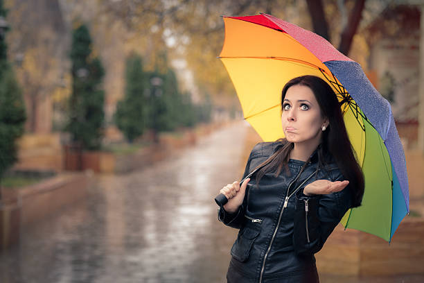 Disappointed Autumn Girl Holding Rainbow Umbrella Sad  fall girl wearing leather jacket outside in rainy weather shower women falling water human face stock pictures, royalty-free photos & images