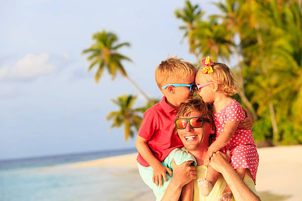 istock happy father with kids on shoulders having fun at beach 488554808