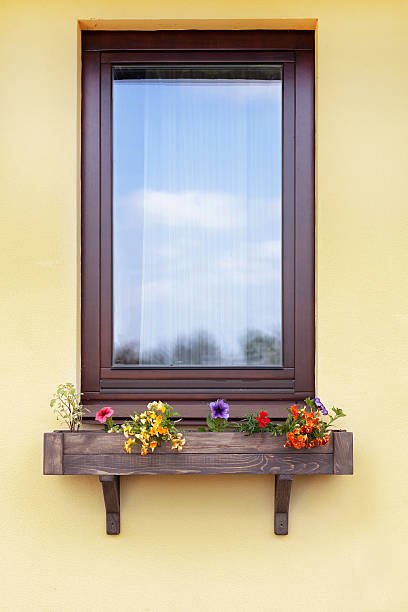 Brown window with flowers in hanging flower pot Brown window with flowers in hanging flower pot double hung window stock pictures, royalty-free photos & images