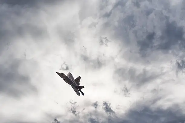 An F22 fighter jet soars across an epic sky.