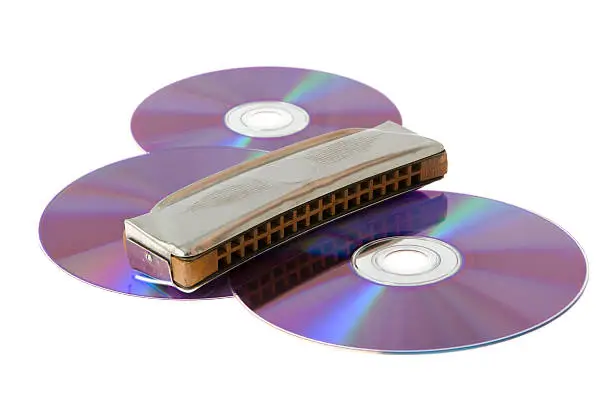 three disks and steel mouth-organ on a white background