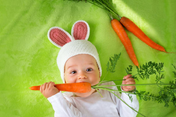baby in kaninchen essen karotten-mütze - baby carrot stock-fotos und bilder