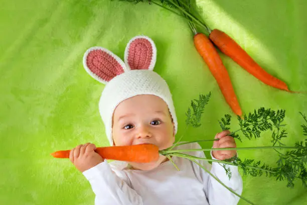 Photo of Baby in rabbit hat eating carrot