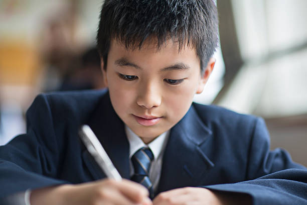istock Japanese student boy working at his classroom desk 488564624
