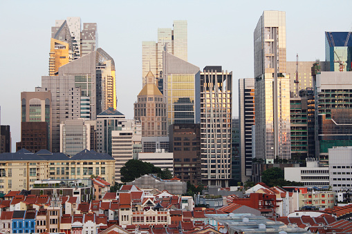 View of Singapore's Chinatown with red rooftop of shop houses and city's financial district and skyscrapers as background in sunset