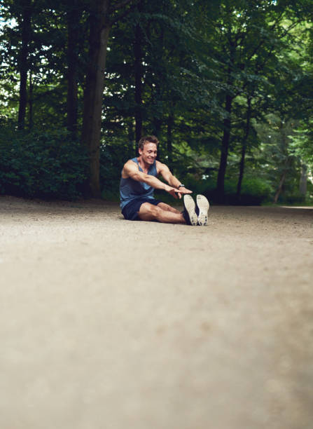 istock Man Sitting on the Ground and Reaching his Toes 488565260