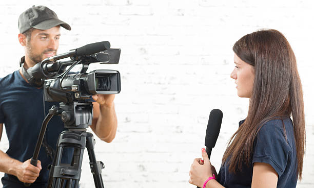 istock young woman journalist with a microphone and a cameraman 488570626