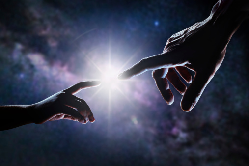 Close up of two hands, adult's and child's, reaching each other like Michelangelo's painting in front of stars and galaxy. Light is shining between father's and son's fingers. High contrast, lens flare.