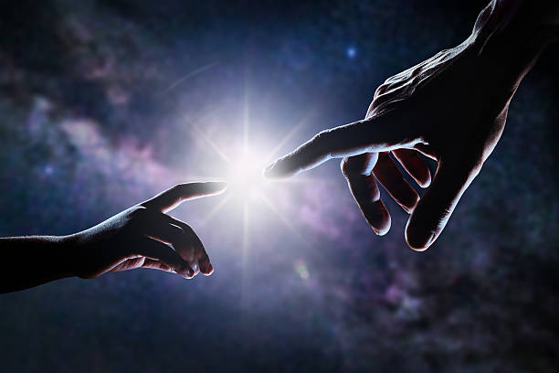 Hand Of God Close up of two hands, adult's and child's, reaching each other like Michelangelo's painting in front of stars and galaxy. Light is shining between father's and son's fingers. High contrast, lens flare. god stock pictures, royalty-free photos & images