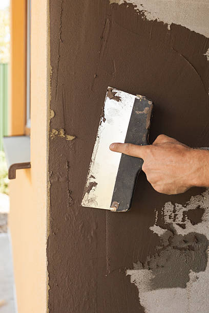 istock Man hand with trowel plastering a house wall 488573530