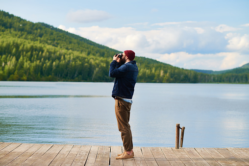 Man standing on pier and taking photo of nature