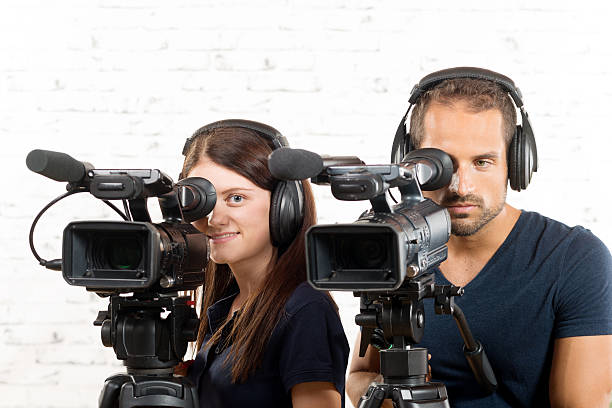 istock young man and woman with professional video cameras 488575192