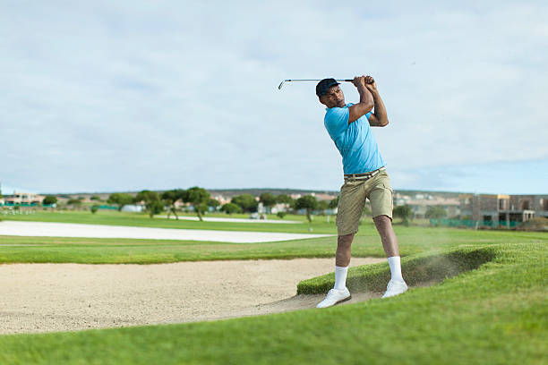 African golfer getting a good shot out of the bunker. stock photo