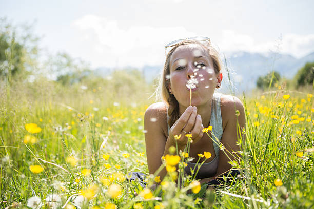 jovem mulher assoar flor no campo - dandelion single flower flower seed imagens e fotografias de stock