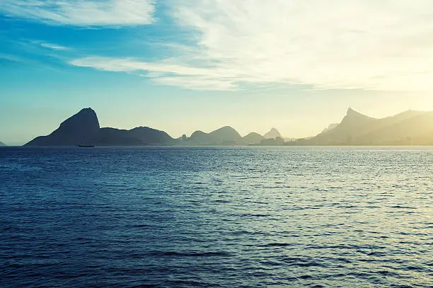 Scenic sunset view of Sugarloaf Mountain and mountain geography from across Guanabara Bay in Niteroi Rio de Janeiro Brazil
