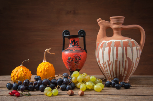 Grapes and pumpkins with ceramic jugs on a table