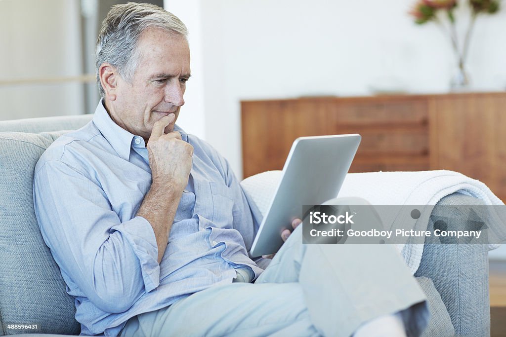 This old dog's learning some new tricks Cropped shot of a senior man using a digital tablet at home Active Seniors Stock Photo