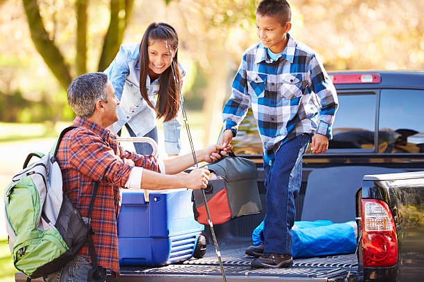 Father And Children Unpacking Truck On Camping Holiday Father And Children Unpacking Truck On Camping Holiday Smiling fishing tackle stock pictures, royalty-free photos & images