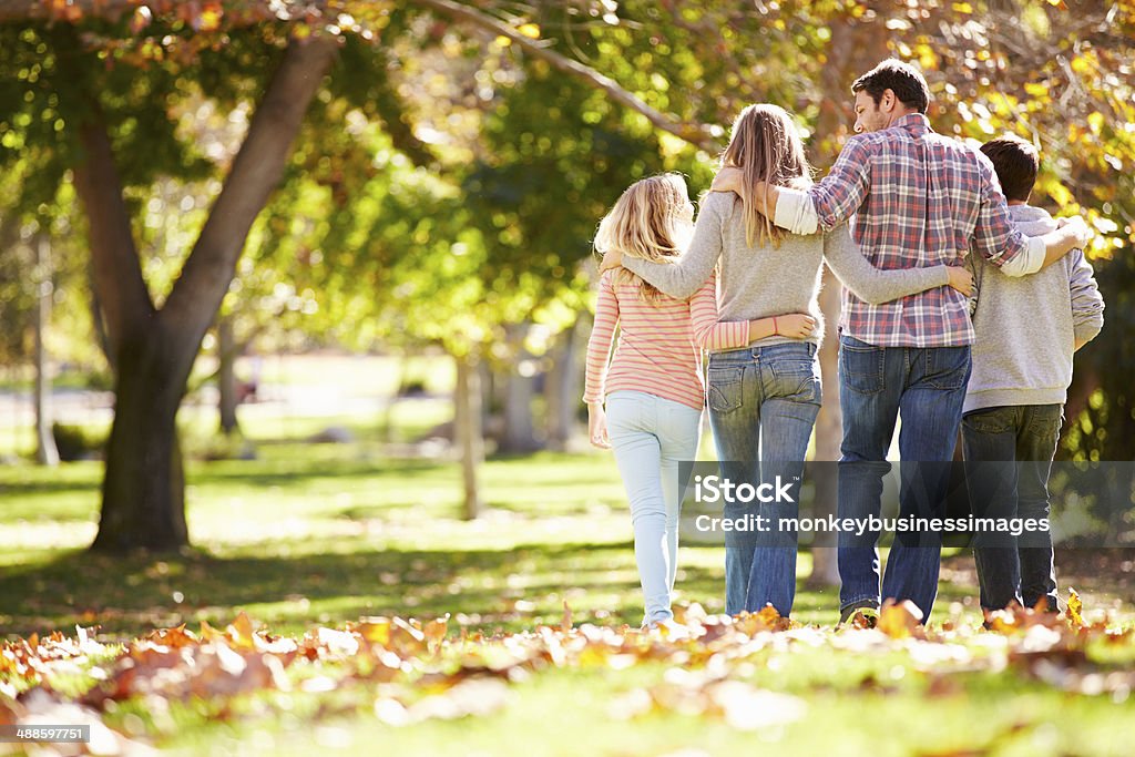 Rear View Of Family Walking Through Autumn Woodland Rear View Of Family Walking Through Autumn Woodland With Arms Around Each Other Family Stock Photo