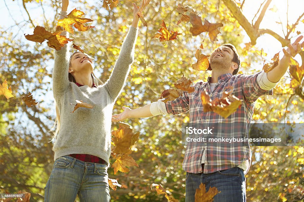 Couple Throwing Autumn Leaves In The Air Couple Throwing Autumn Leaves In The Air Smiling Autumn Stock Photo