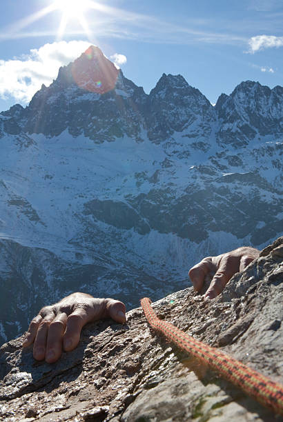 istock Hands of climber grasp rock ledge, mountains behind 488597926