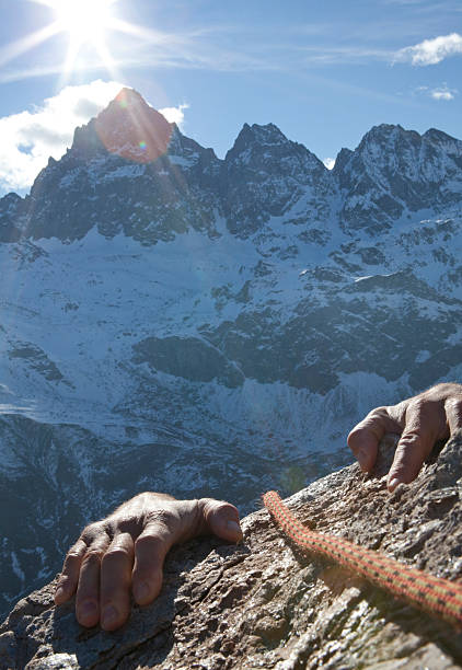 istock Hands of climber grasp rock ledge, mountains behind 488598064