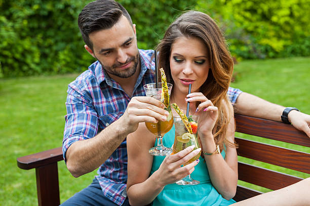 Couple sitting  in garden and having colorful drinks. stock photo