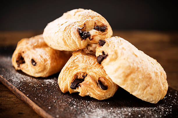 chocolate bread Rustic chopping board with pain au chocolat. pain au chocolat stock pictures, royalty-free photos & images