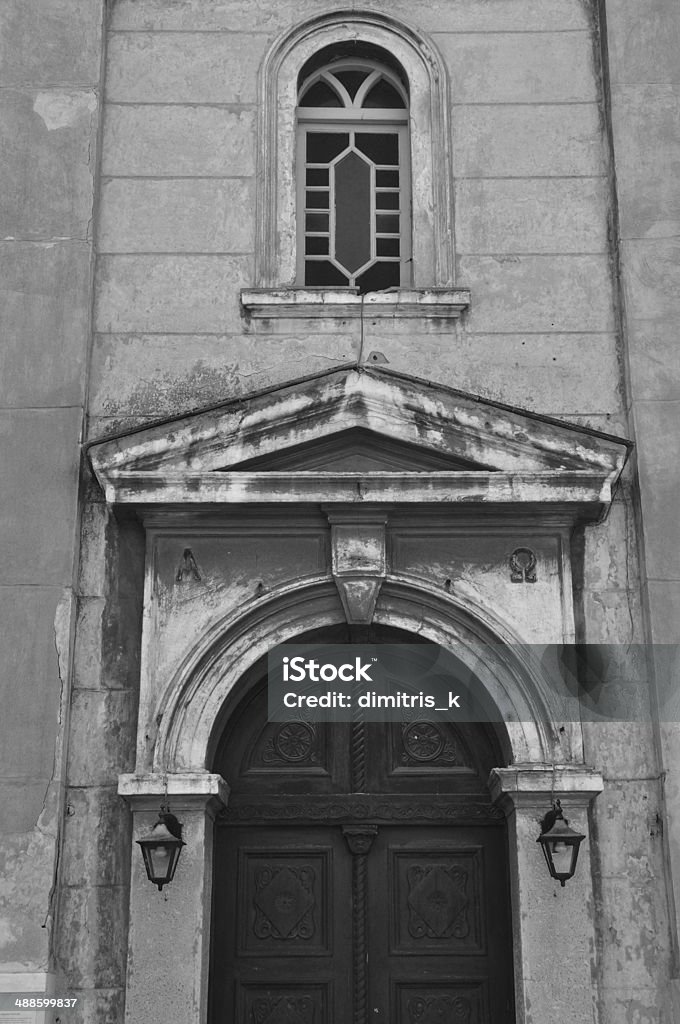 alpha and omega Byzantine church exterior with alpha and omega engraved inscription. Arched wooden gate and weathered wall black and white. Alphabet Stock Photo