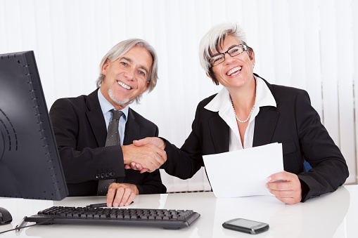 Smiling senior partners sitting together at a desk having a business meeting