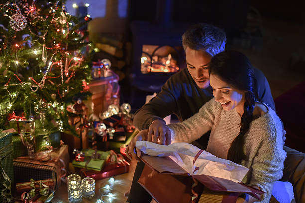 istock couple opening a gift  near christmas tree lit up 488601748