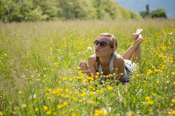 giovane donna gioca con i fiori nel campo - dandelion snow immagine foto e immagini stock