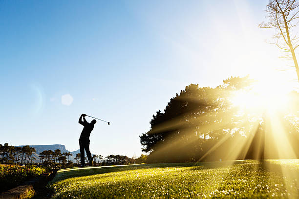 silhouette der junge golfer schaukeln auf wunderschönen, sonnendurchfluteten golfplatz - golfschwung stock-fotos und bilder