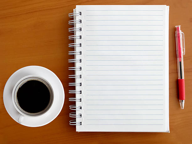istock Notebook, pen and cup of coffee on wooden table 488613028