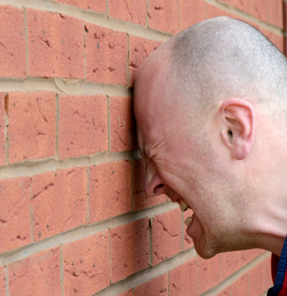 a man banging his head agaist the wall in frustration