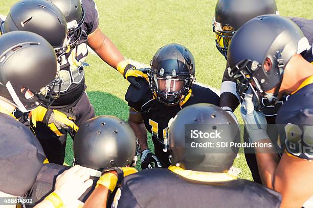 Photo libre de droit de Équipe De Football Américain Professionnelle Parle Dans Huddle Sur Terrain De Football Américain En Marge banque d'images et plus d'images libres de droit de 2015