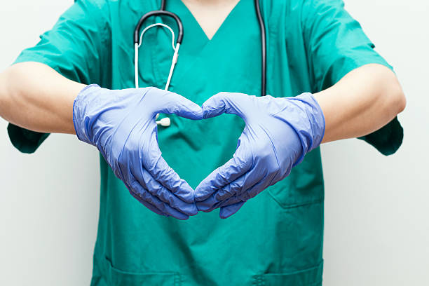 Doctor Making Heart Shape With Hands Doctor making heart shape with hands, vertical heart surgery photos stock pictures, royalty-free photos & images