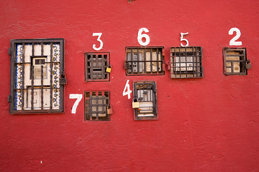 Numbers for the apartments and intercoms on bright coral colored  wall: two, three, four, five, six, seven. Antigua, Guatemala.