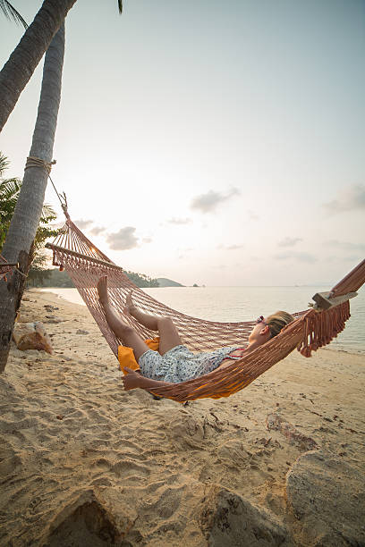 istock Young woman relaxing on hammock in tropical beach 488617067