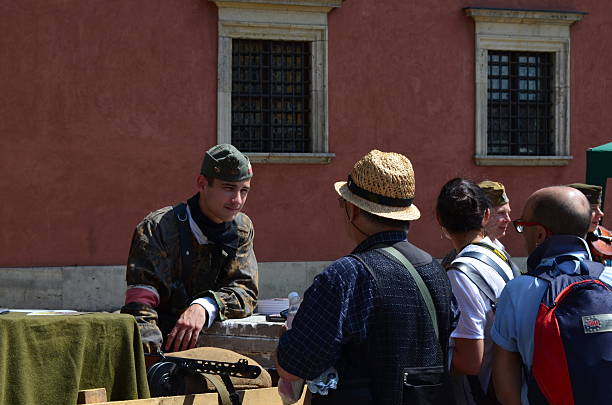 Warsaw, Poland - August 2, 2015: A young man dressed like a member of the resistance speaking to a passer-by at the Old Town around noon.