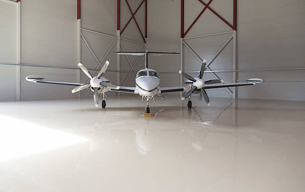 Small aircraft parked in a hangar Small two-propeller aircraft parked in a big hangar airplane hangar stock pictures, royalty-free photos & images