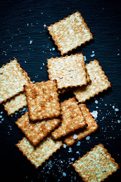 istock Crispy golden crackers with salt on dark stone background 488635468