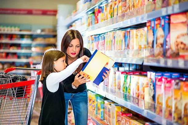 Photo of Mother and daughter checking food labeling in supermarket